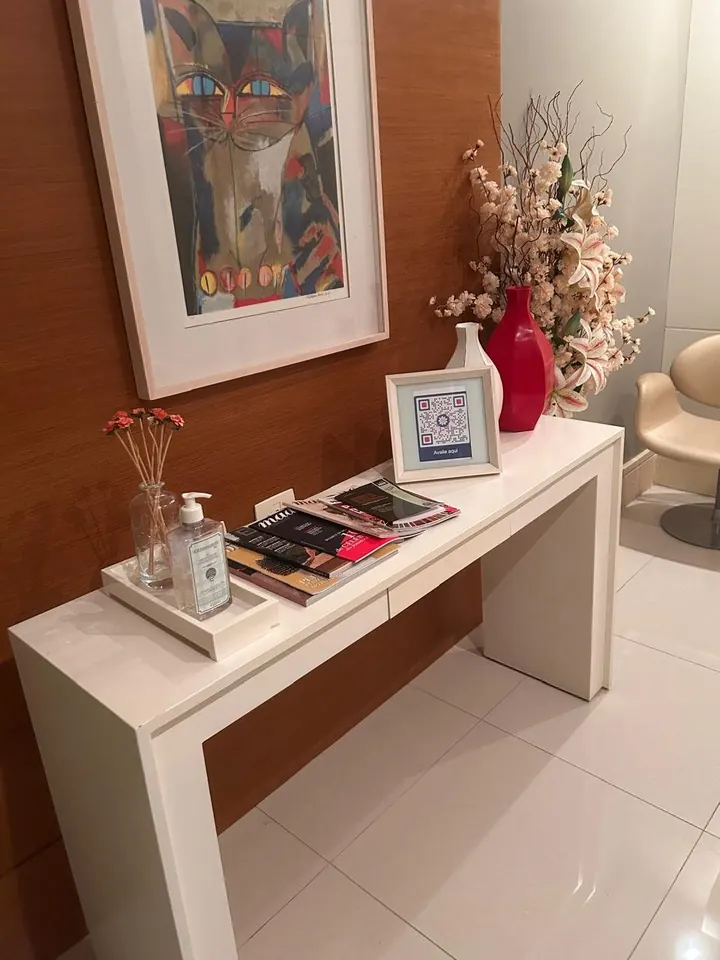 Aparador da recepção com flores, revistas e álcool em gel